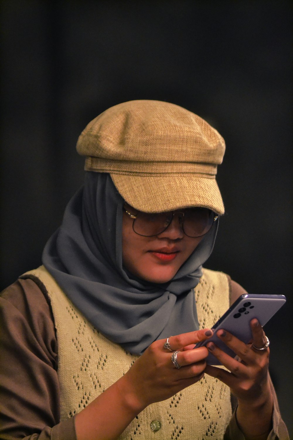 a man wearing a hat and glasses holding a phone
