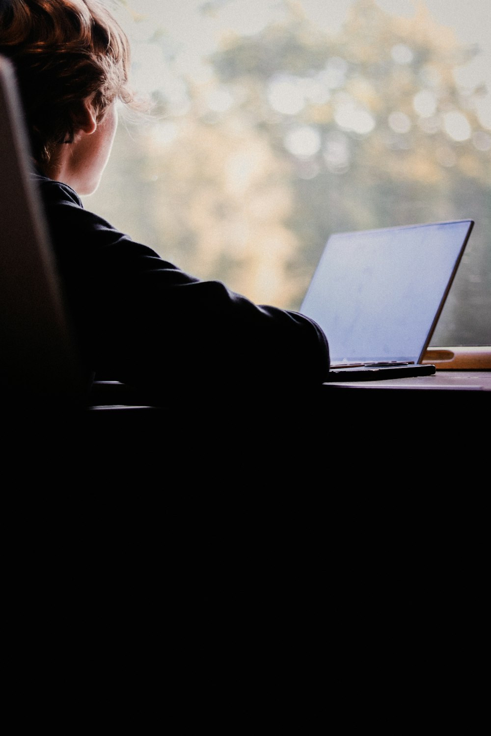 Una persona sentada en un escritorio con una computadora portátil