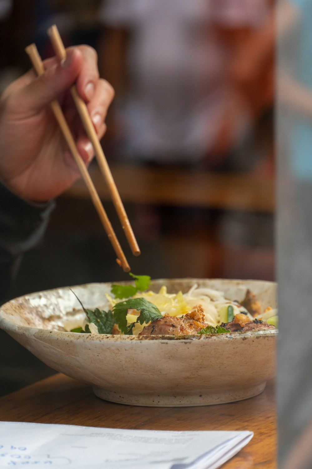 a person holding chopsticks over a bowl of food