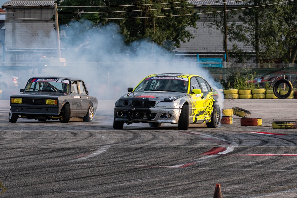 a group of race cars on a road with smoke coming out of the tires