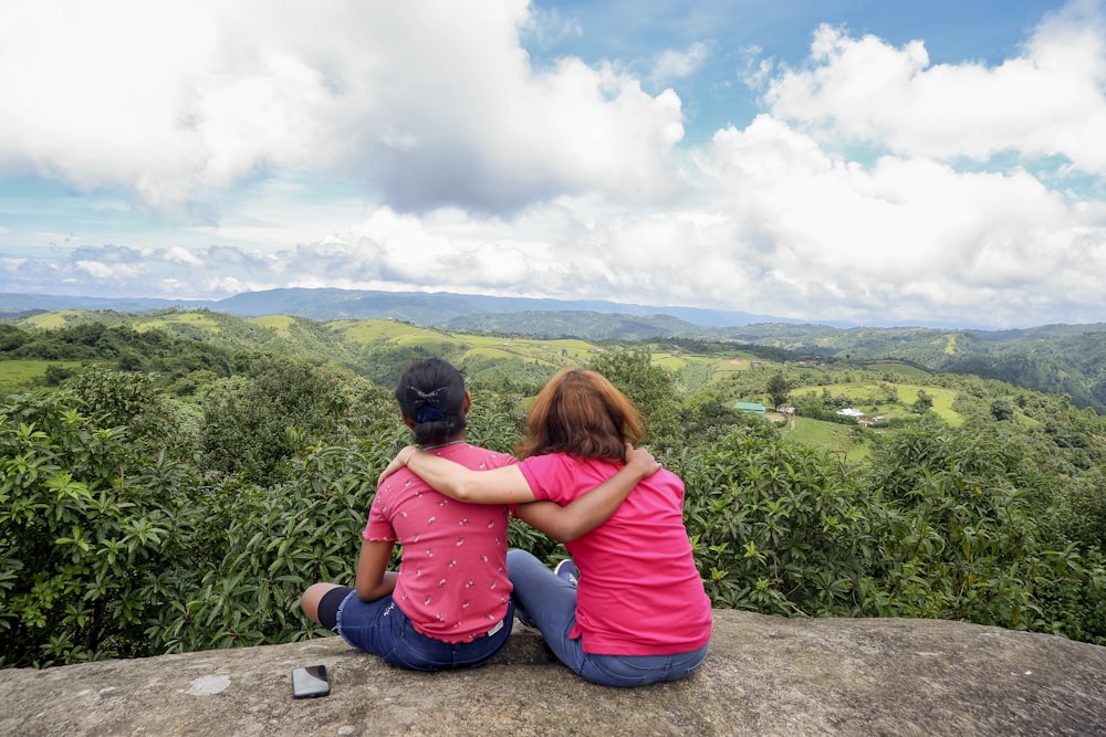 Dos mujeres sentadas en una cornisa con vistas a un valle