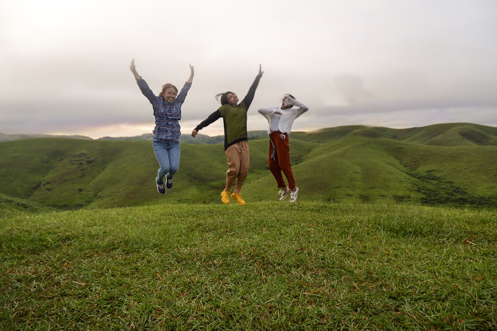 a group of people jumping in the air on a grassy hill