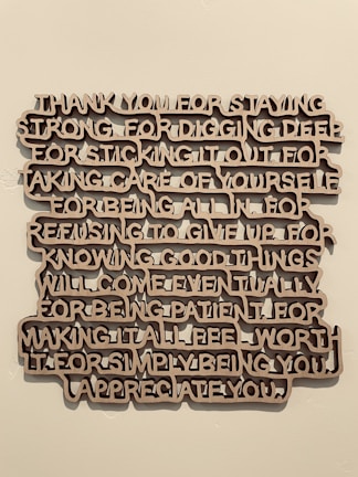 A piece of wall art with text expressing gratitude and appreciation, crafted in a three-dimensional style with brown letters casting shadows against a light wall.