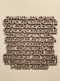 A piece of wall art with text expressing gratitude and appreciation, crafted in a three-dimensional style with brown letters casting shadows against a light wall.