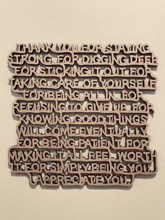 A piece of wall art with text expressing gratitude and appreciation, crafted in a three-dimensional style with brown letters casting shadows against a light wall.