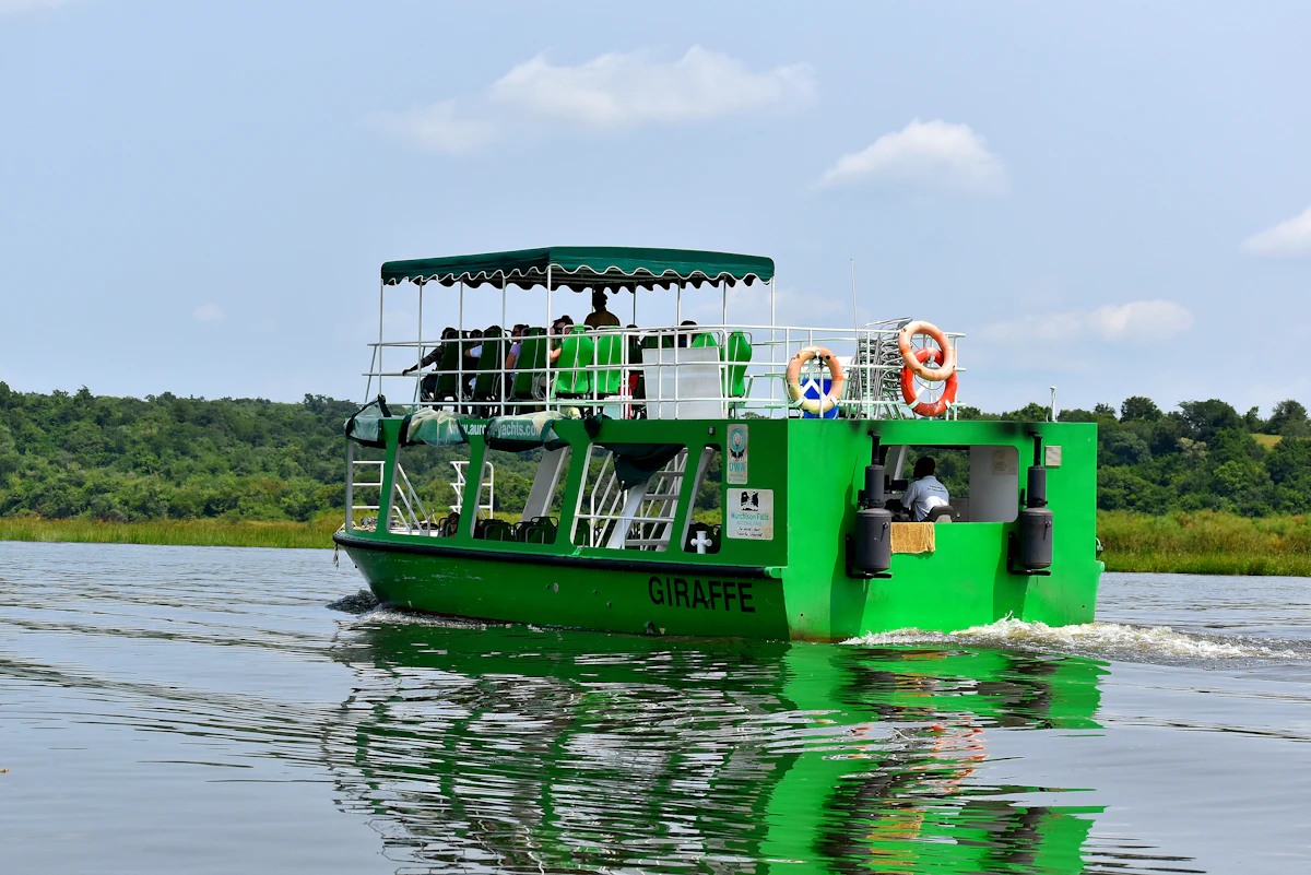 A green launch boat carrying visitors on the Victoria Nile in Murchison Falls National Park