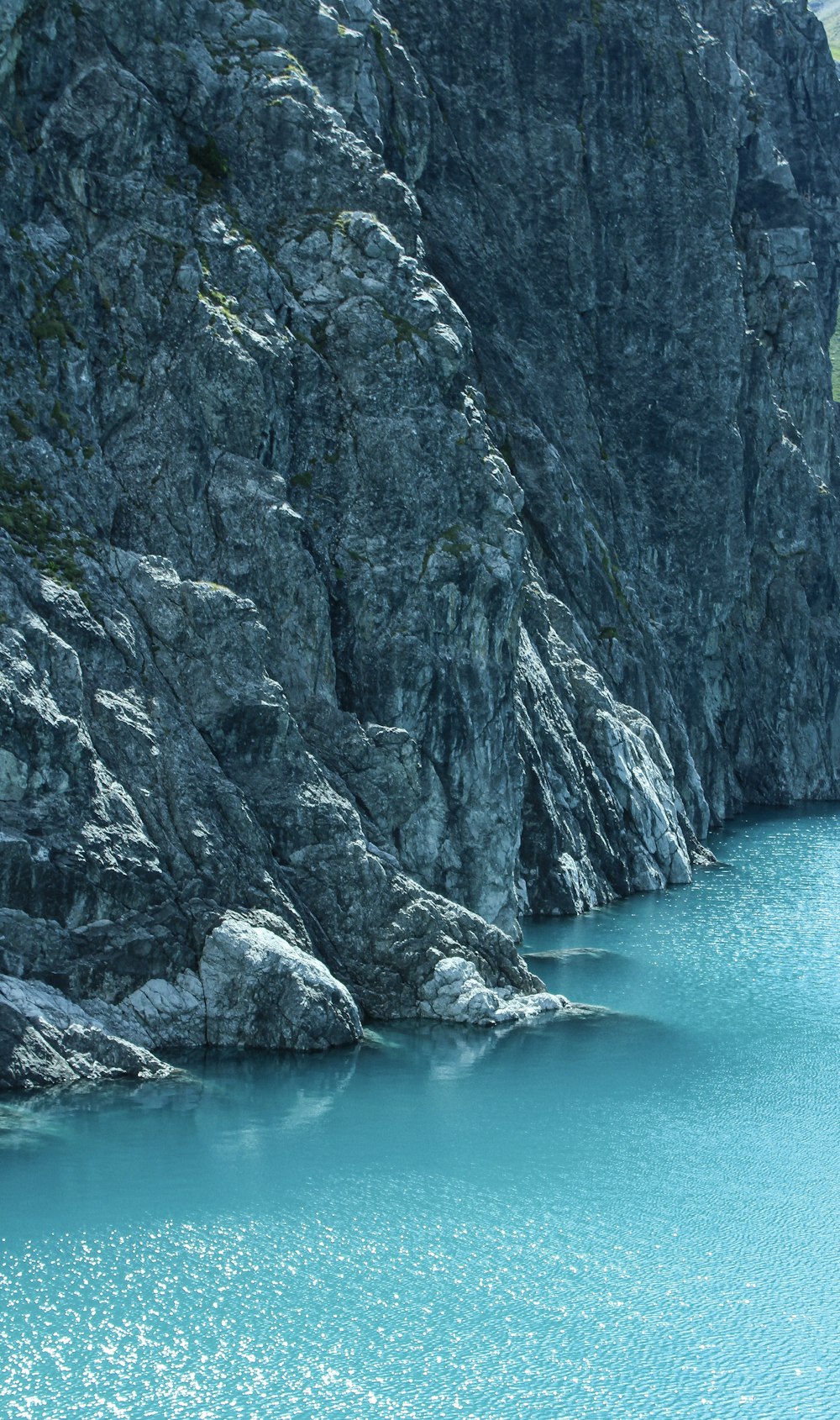 a rocky cliff next to a body of water