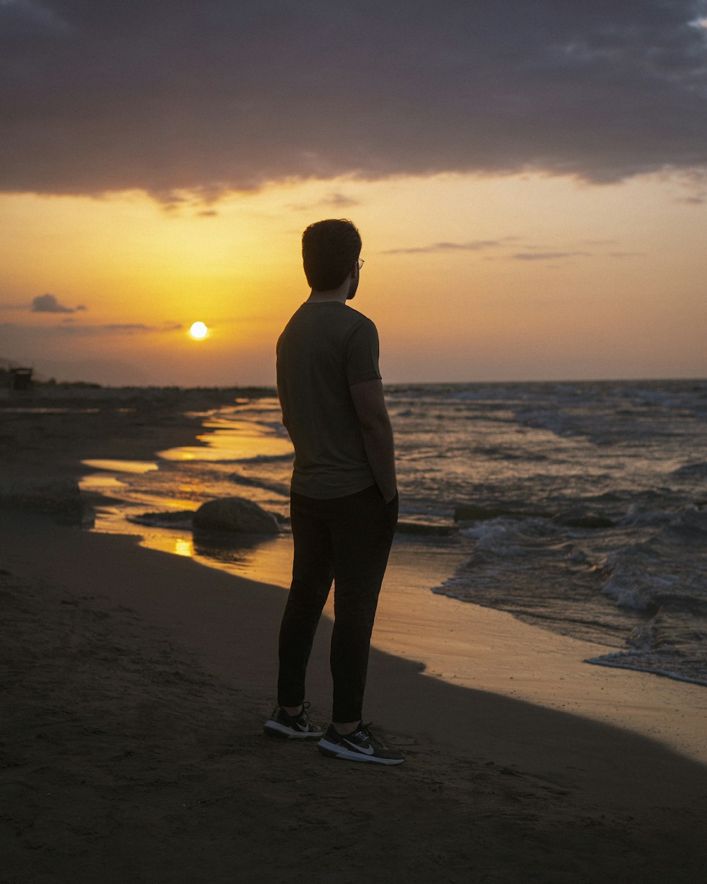 a person standing on a beach looking at the sunset