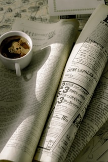 A vintage newspaper spread open on a rustic wooden table with a steaming cup of coffee nearby.