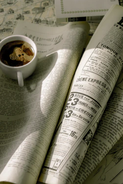 A dimly lit café corner with an open vintage magazine and a steaming cup of coffee under soft violet light.