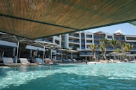 Modern hotel pool area with sun loungers and a view of the ocean.