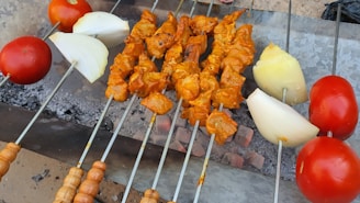A sizzling skewer of marinated chicken turning over an open flame grill.