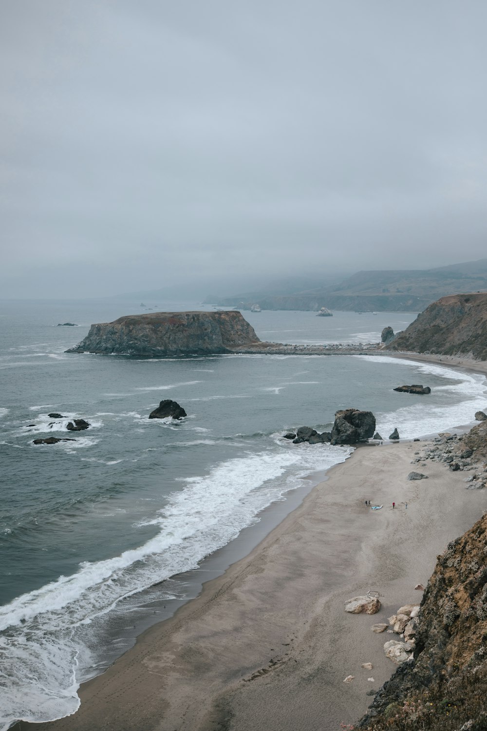 a rocky beach with a body of water and a rocky cliff