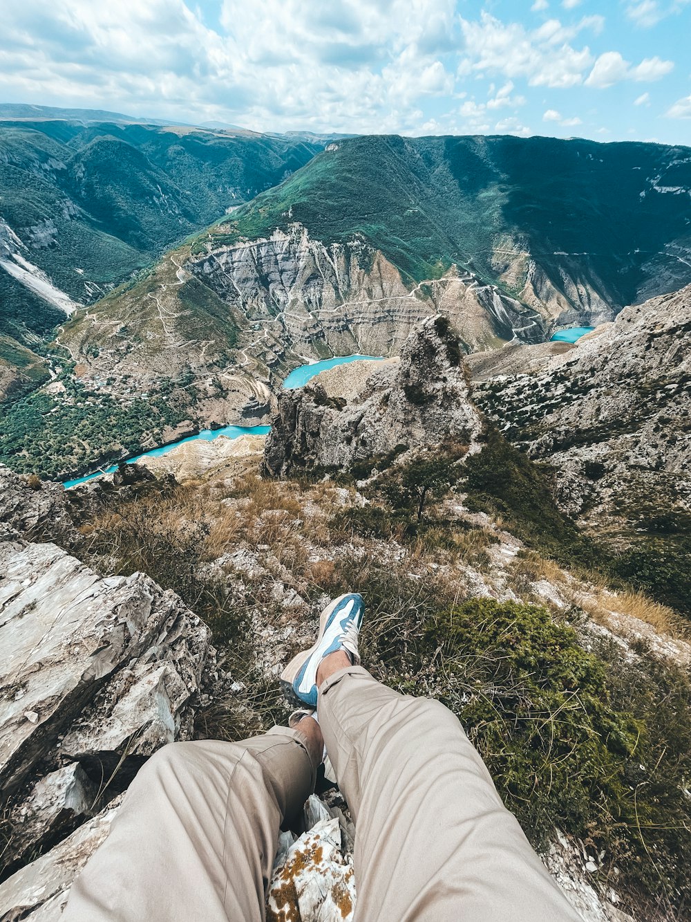 a person sitting on a rock overlooking a valley with a river running through it