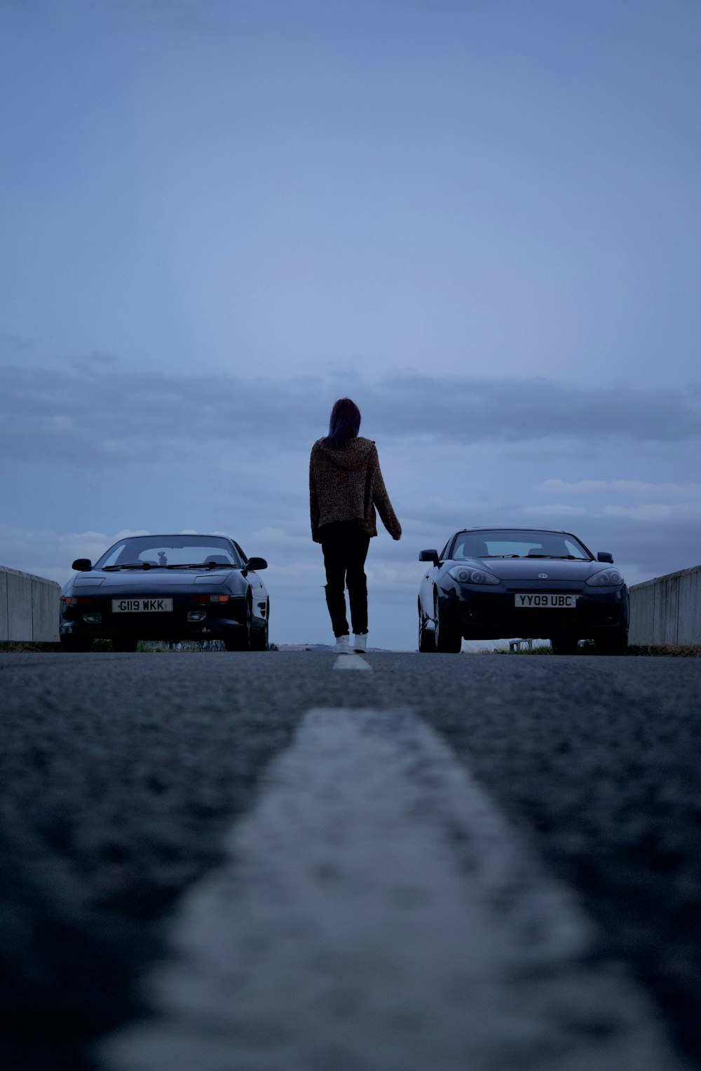 a man standing next to two cars