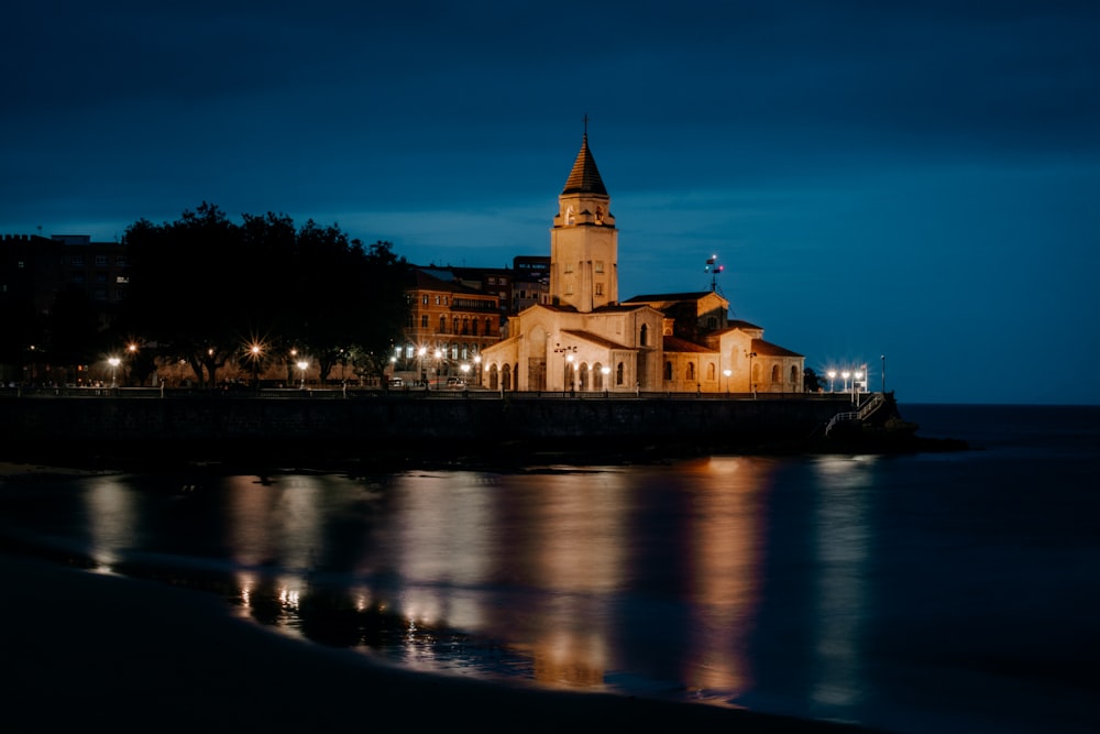 a building with a tower by a body of water at night