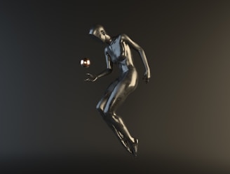 A stylized, metallic humanoid figure appears to be floating or suspended in mid-air against a dark background. The figure is interacting with a small, reflective sphere hovering near its hand.