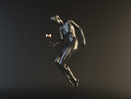 A stylized, metallic humanoid figure appears to be floating or suspended in mid-air against a dark background. The figure is interacting with a small, reflective sphere hovering near its hand.