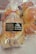 Transparent plastic bags containing freshly baked bread rolls are tied with red string. A label on the bag displays a logo and phone numbers for ordering.