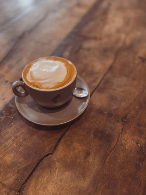 A warm, inviting cup of cappuccino with creamy foam art on a rustic wooden table.