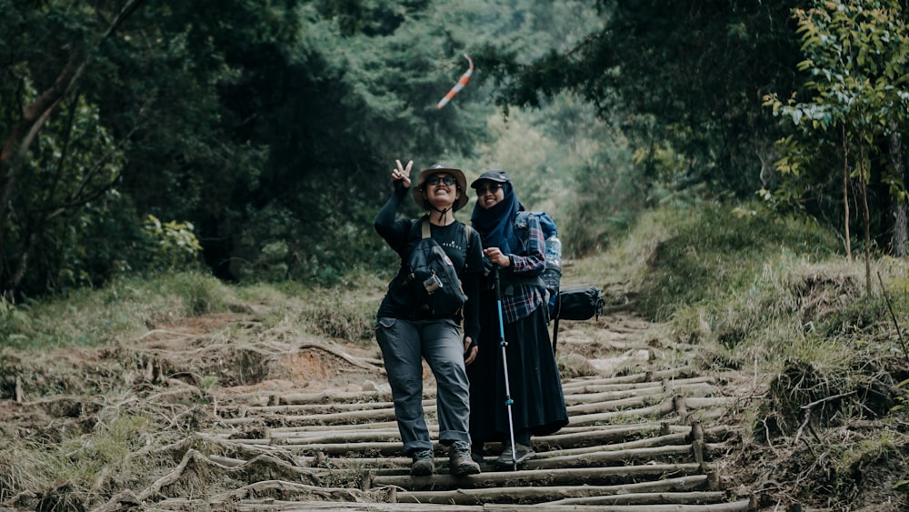 a man and woman standing on a railroad track with a stick and a stick