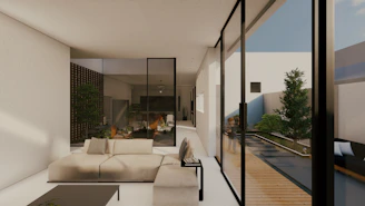 A modern, minimalist living room with natural light and green plants blending indoor and outdoor spaces.