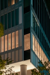 Modern commercial building facade with sleek metal and glass elements illuminated at dusk.
