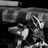 A detailed view of a model robot or mech with angular armor plating and a sleek design. The background features blurred storage containers, creating a sense of focus on the mechanical figure. The image is in black and white, highlighting the contours and details of the design.