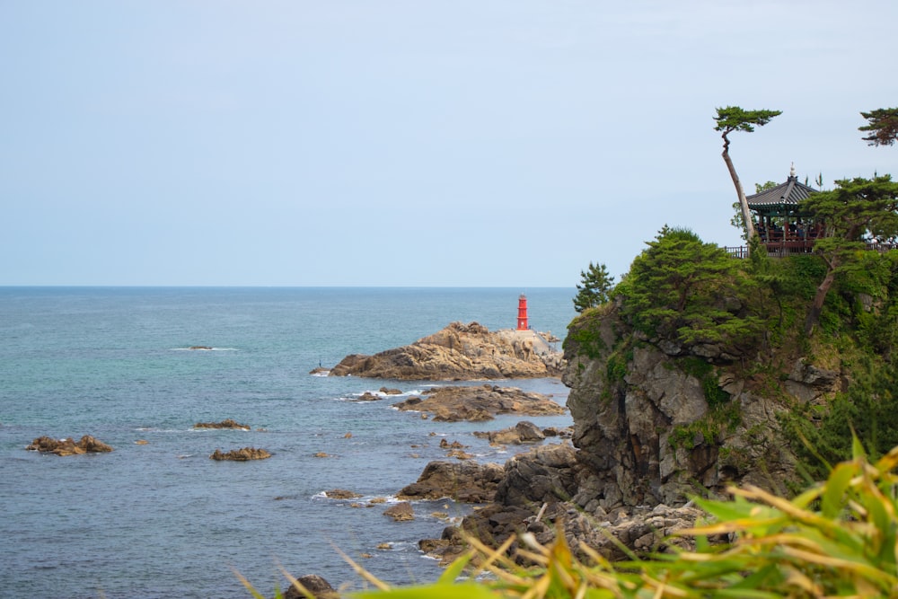 Ein felsiger Strand mit einem roten Leuchtturm