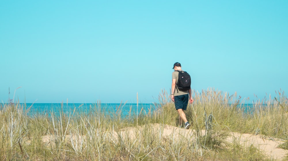 a man walking on a path in a field of tall grass