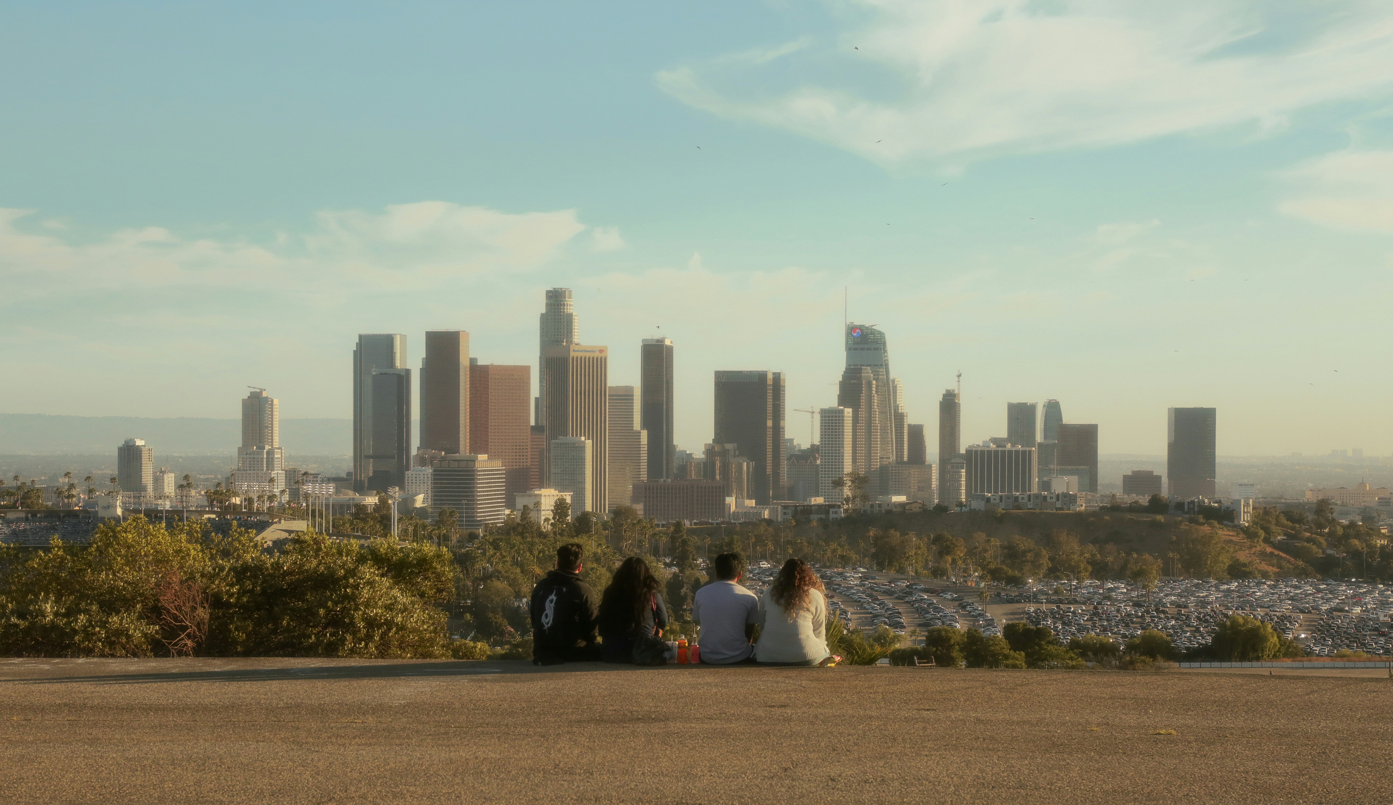 a group of people sitting on a ledge overlooking a city