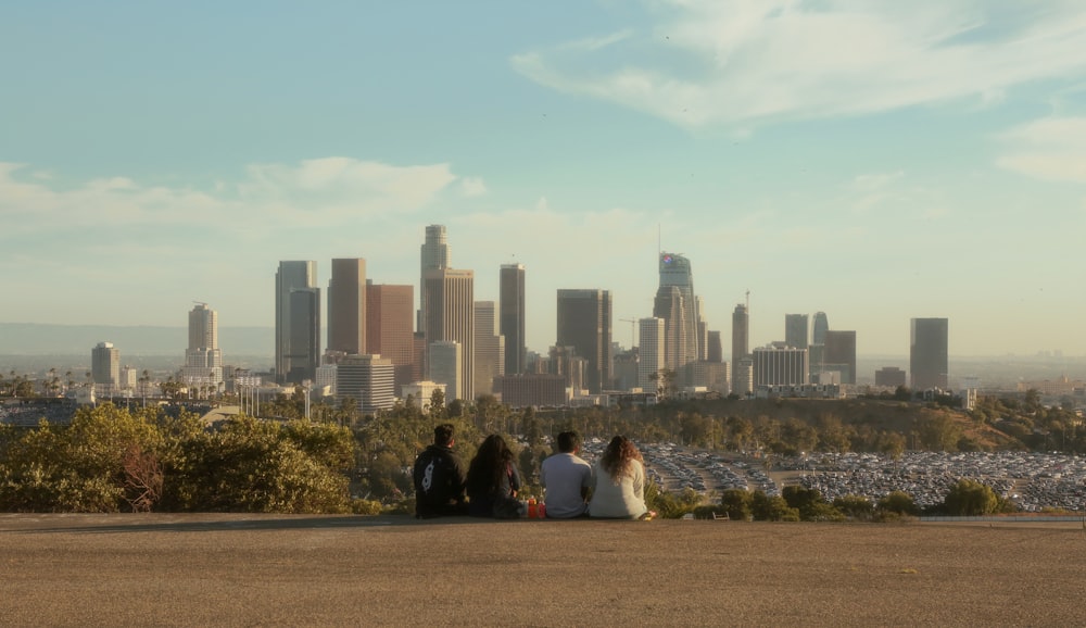 a group of people sitting on a ledge overlooking a city