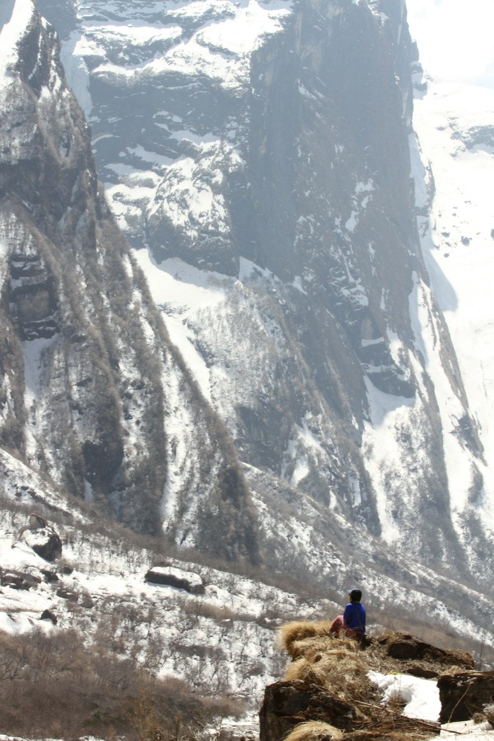 a person sitting on a rock in front of a mountain