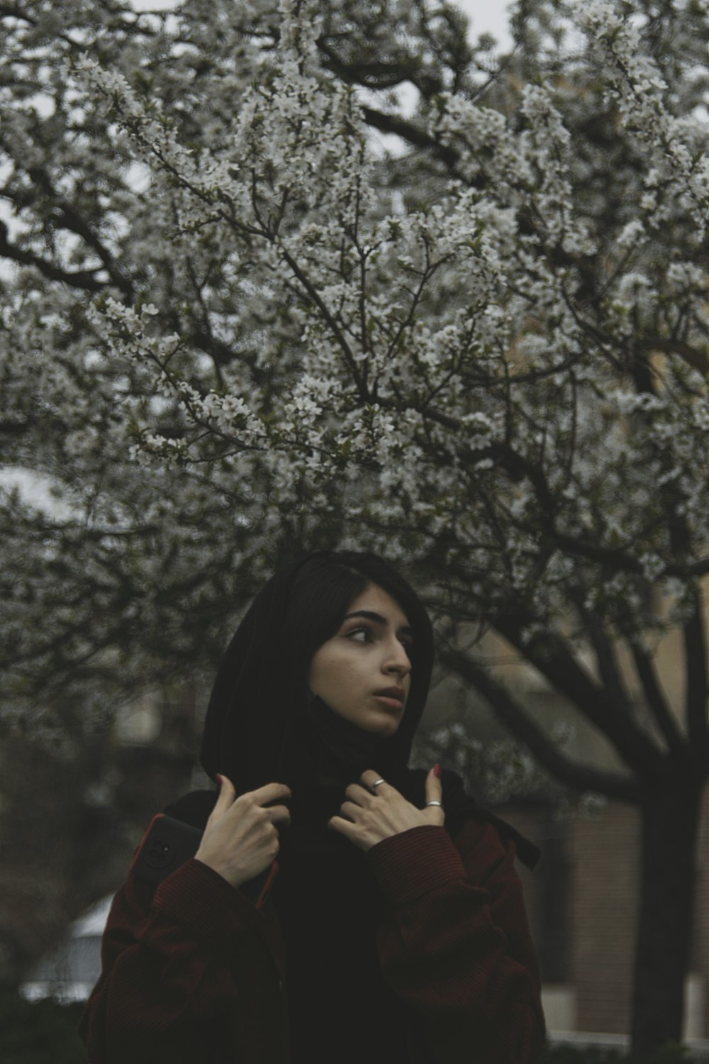 a woman standing in front of a flowering tree