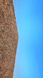 View of a pitched roof covered with dark slate tiles against a clear blue sky.