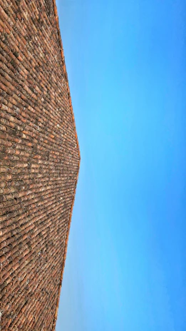 View of a pitched roof covered with dark slate tiles against a clear blue sky.