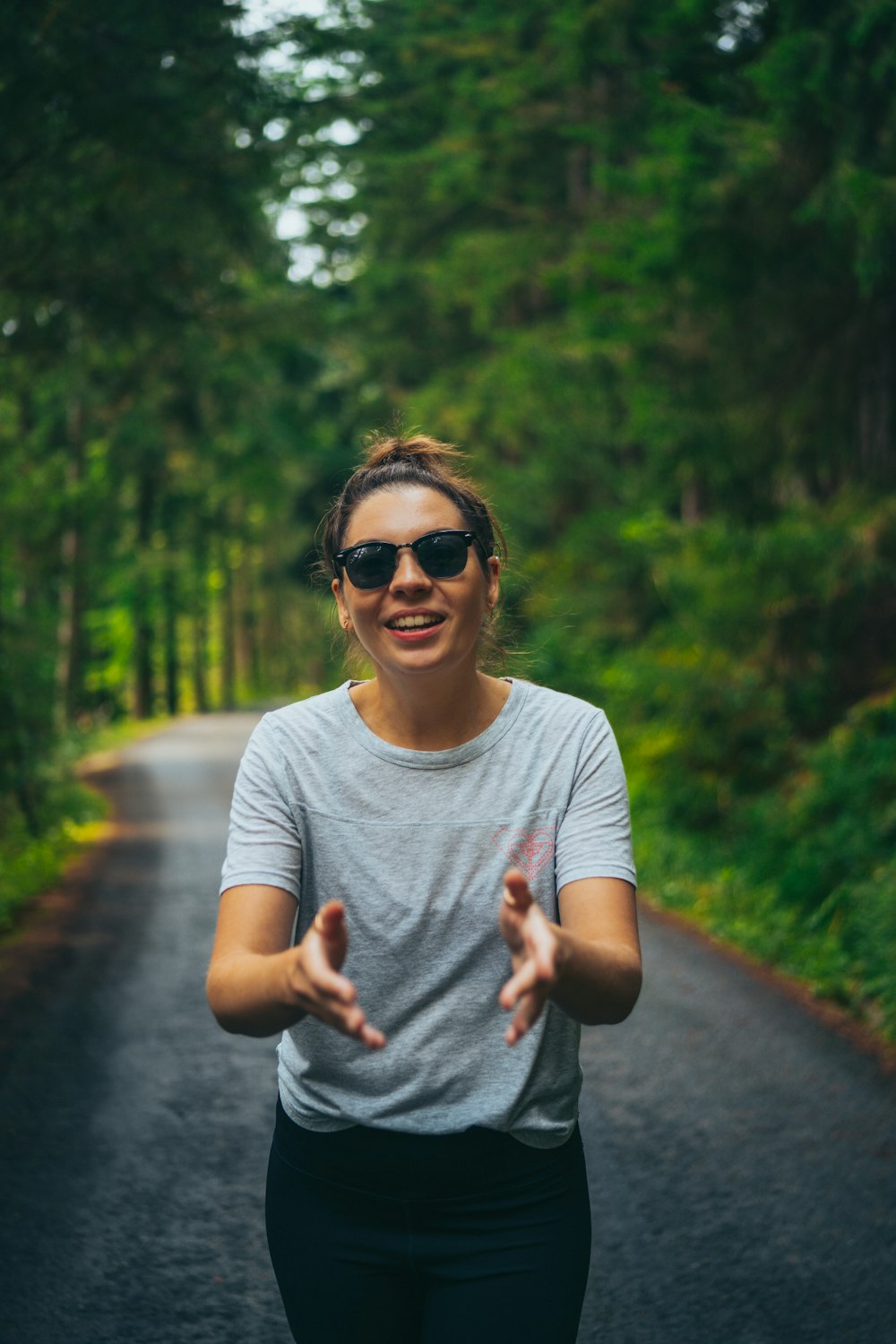 a person wearing sunglasses and standing on a path in the woods