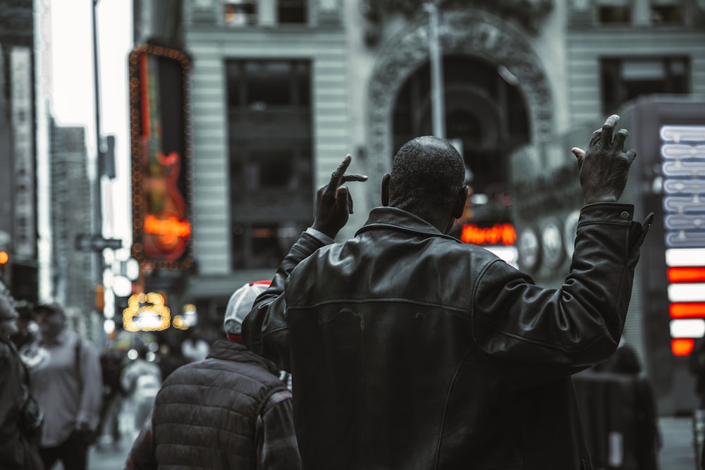 Una persona con un abrigo negro sosteniendo las manos hacia arriba