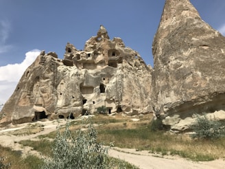 MG TURIZM Ancient cave dwellings carved into soft volcanic rock under a clear blue sky
