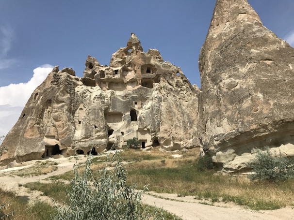 MG TURIZM Ancient cave dwellings carved into soft volcanic rock under a clear blue sky