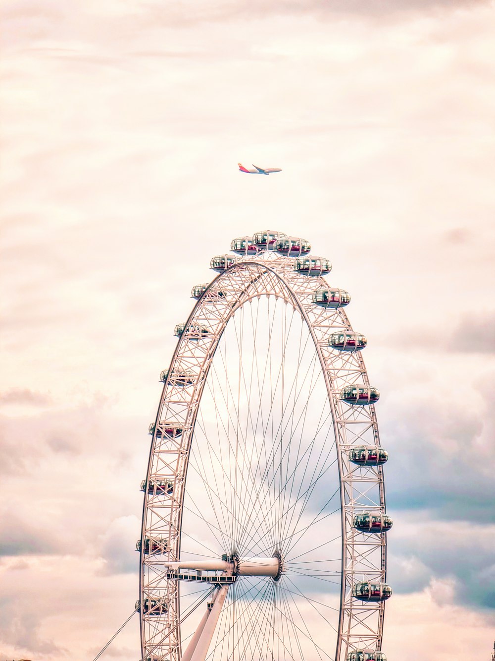 a ferris wheel with a plane flying by