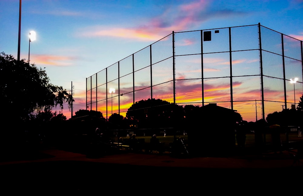 a large metal fence with a sunset in the background