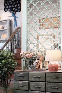 A detailed shot of hands painting a vintage dresser in a calming sage green.