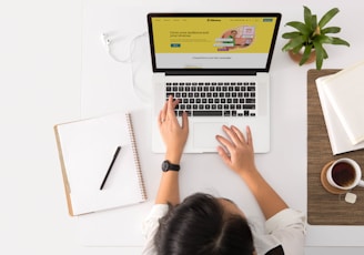 a person sitting at a desk with a laptop and a coffee cup