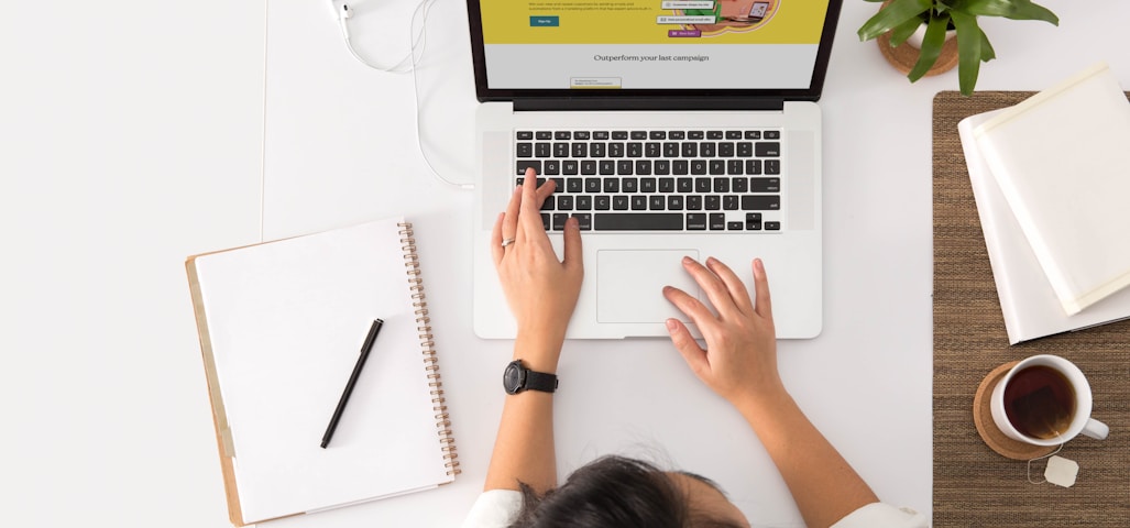 a person sitting at a desk with a laptop and a coffee cup