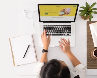 a person sitting at a desk with a laptop and a coffee cup