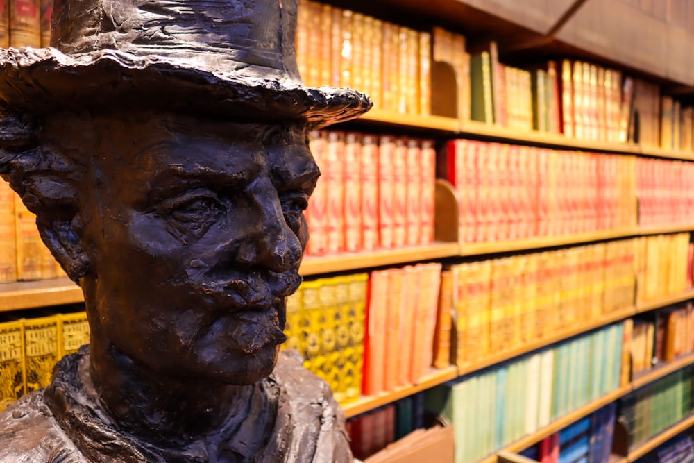 a statue of a person in front of a book shelf