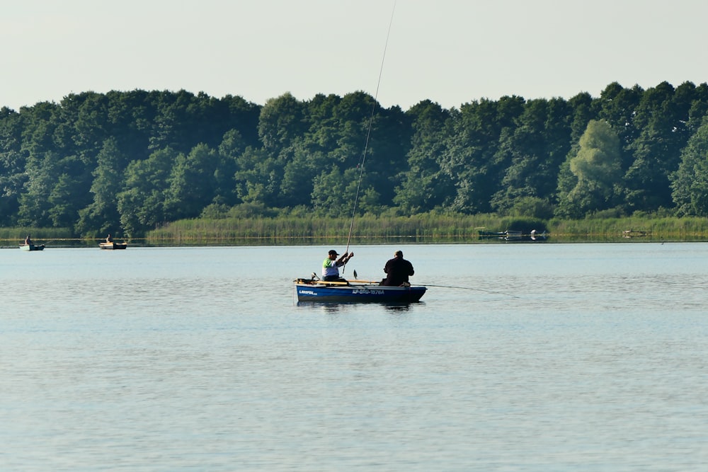 a couple of people fishing on a boat in a lake