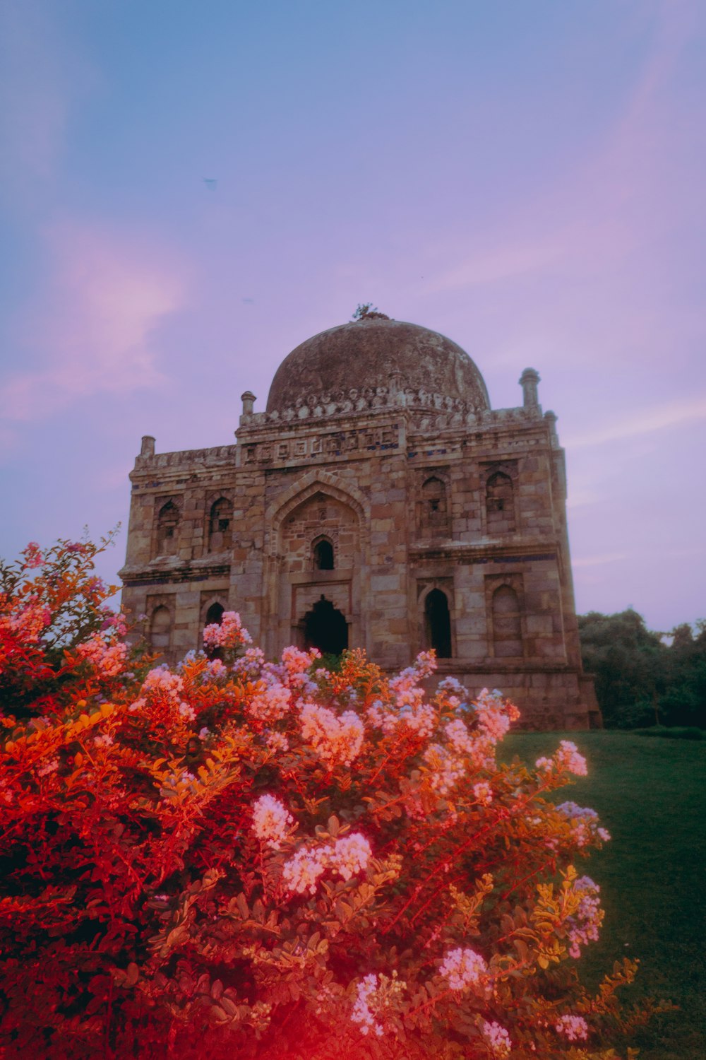 a large stone building with a dome with Lodi Gardens in the background