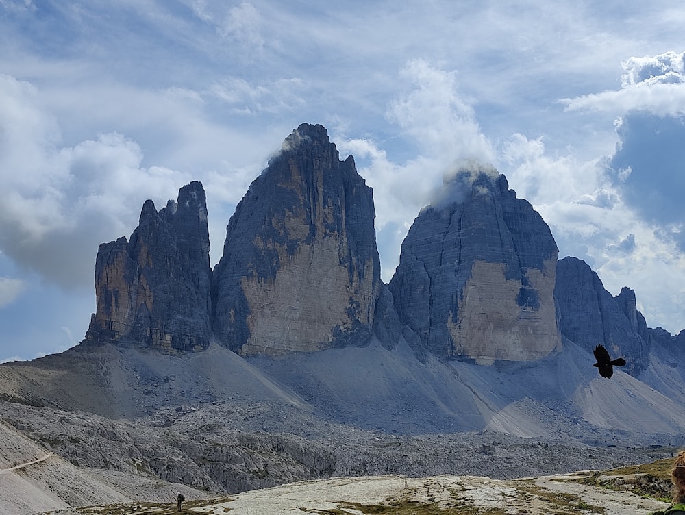 a rocky mountain with a valley below with Tre Cime di Lavaredo in the background